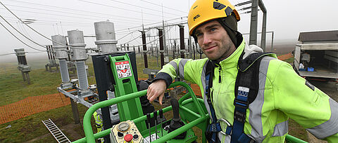 Monteur in Schutzausrüstung bei Arbeiten an Umspann- und Stromnetzanlage