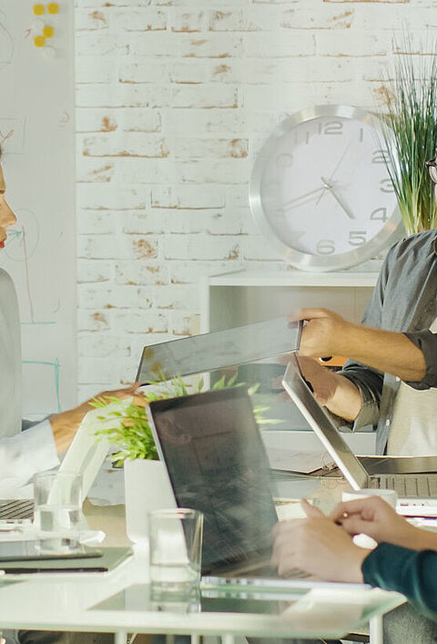 Teammeeting im Büro mit Laptop und Präsentation am Tisch