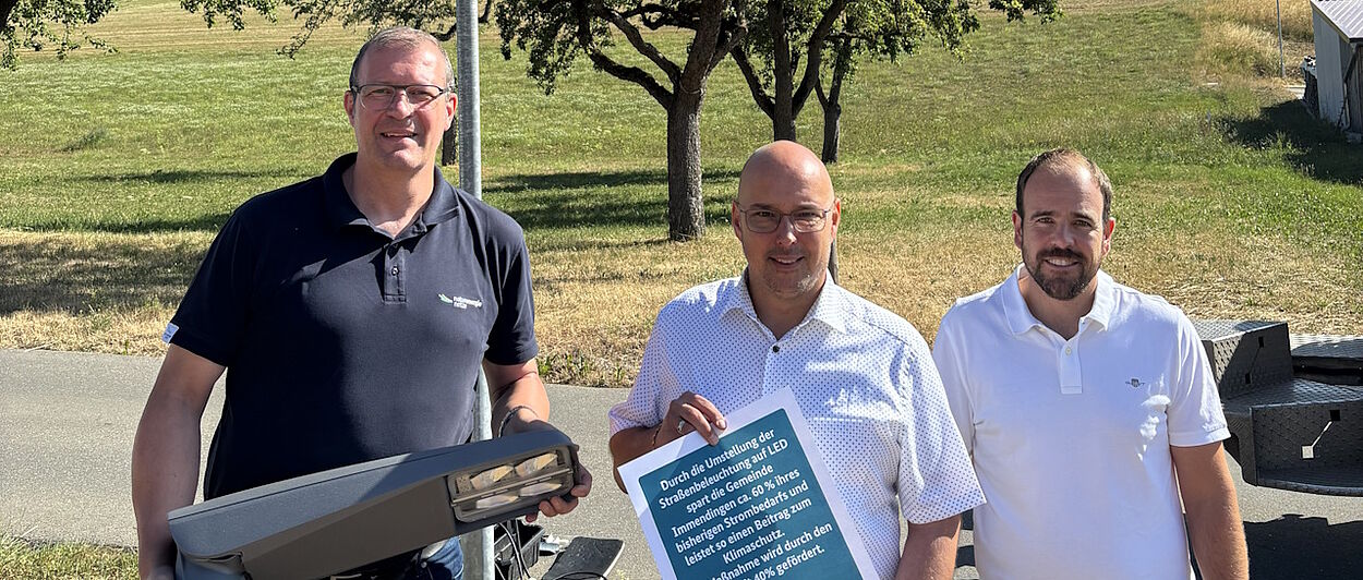 Drei Personen mit LED-Straßenlaterne und Urkunde