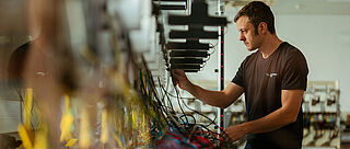 Mitarbeitende Person arbeitet an einer elektrischen Prüfanlage