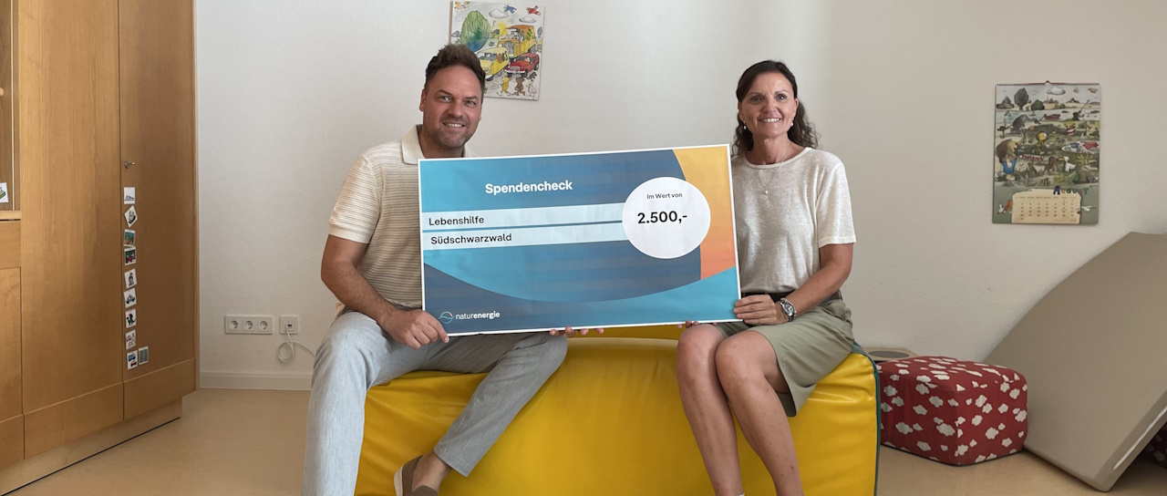 Mann und Frau sitzend mit Spendenscheck