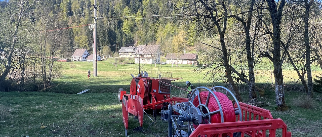 Baumaschinen auf Wiese vor Strommaste